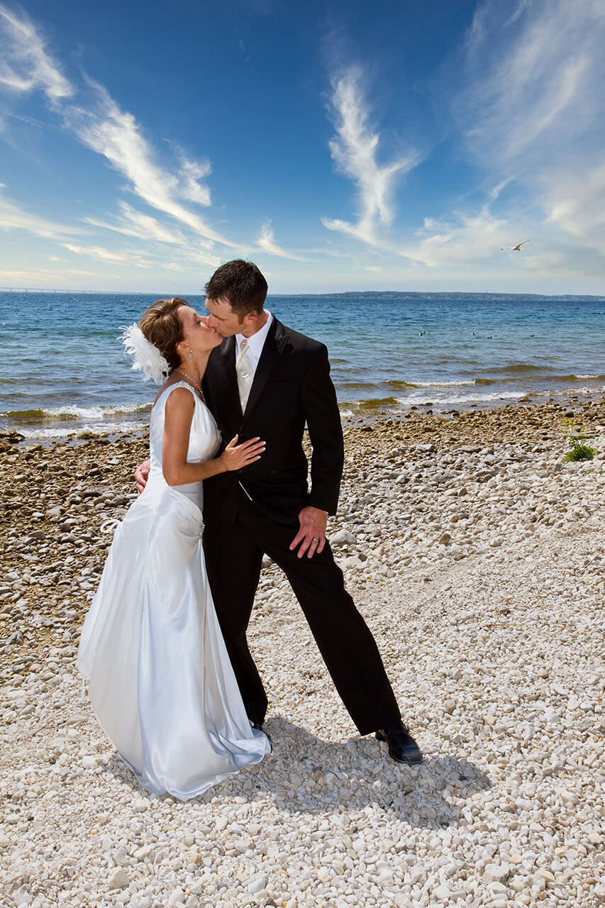 Briding groom kissing on a rocky beach