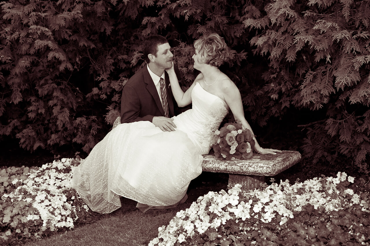 Bride and groom posing on a stone bench