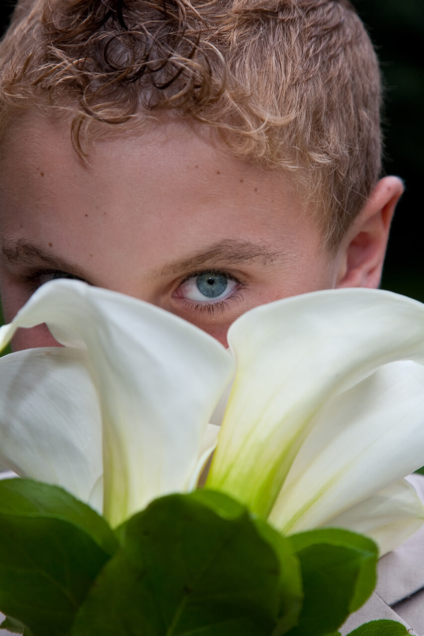 Young boy hiding behind flowers