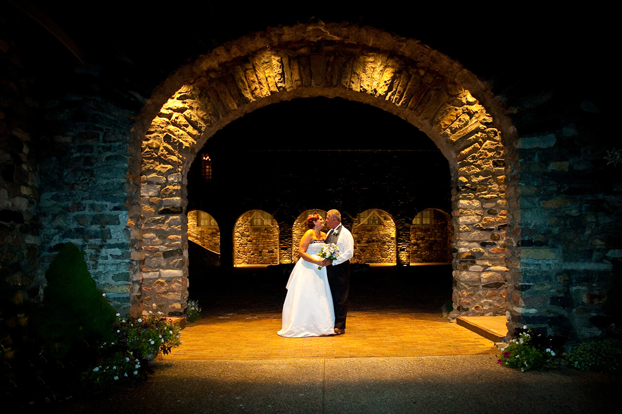 Bride and groom embracing under an arch at Castle Farms